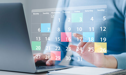 Eine Person am Laptop mit der Grafik eines Kalenders im Vordergrund