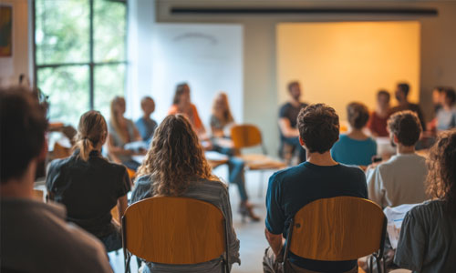 Viele Menschen sitzend auf Stühlen in einem Veranstaltungsraum